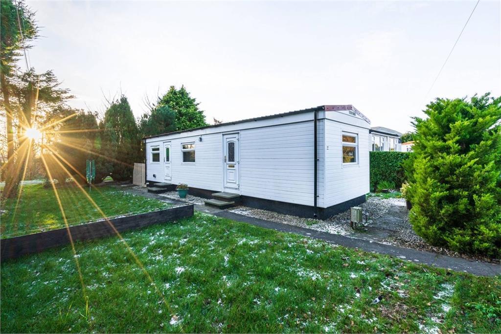 A white motorhome with green grass shown in front of it.