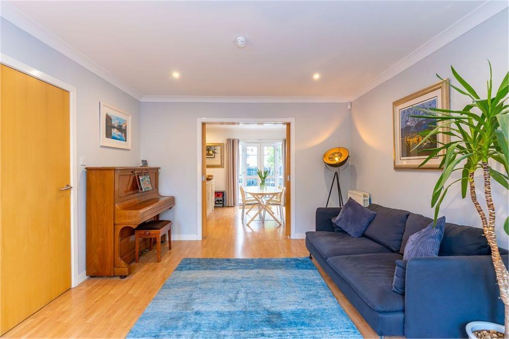 A spacious living room with navy sofa, piano, blue rug, and laminate flooring.